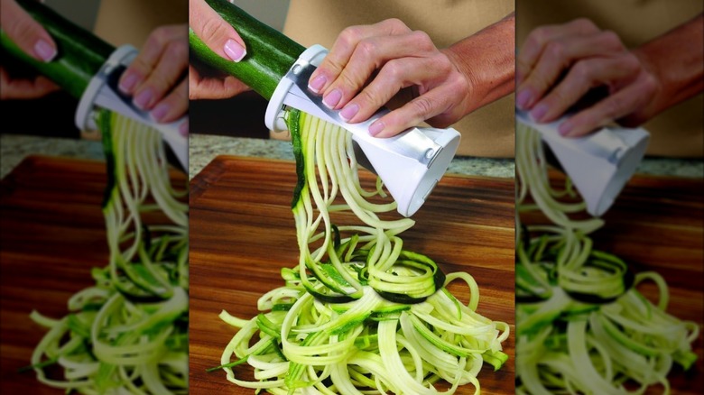 A person spiralizing zucchini with an Ontel Veggetti Spiral Vegetable Cutter