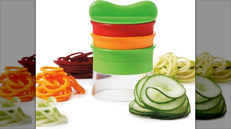 An OXO Good Grips hand-held spiralizer with cut veggies