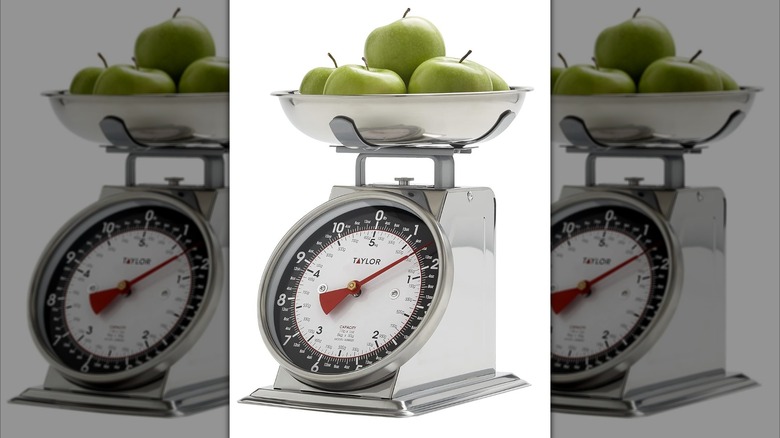 Taylor Mechanical Kitchen Scale with green apples on a white background