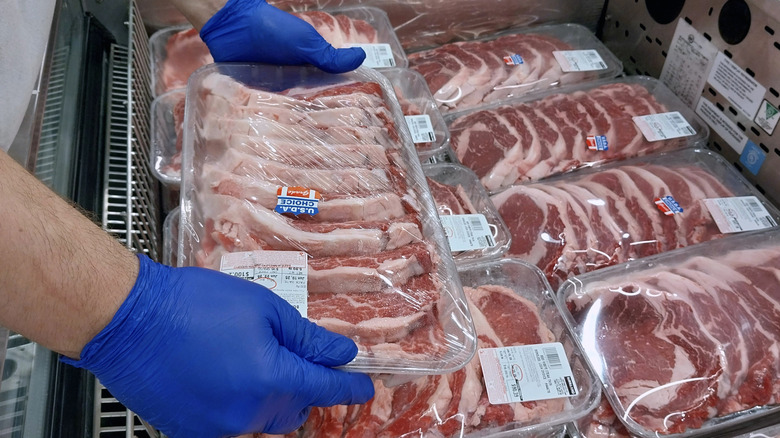 Worker handing packages of steak at Costco