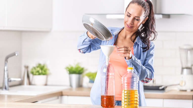 person pouring cooking oil into disposable containers