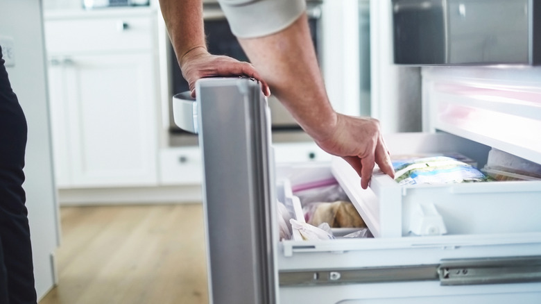person opening a freezer drawer
