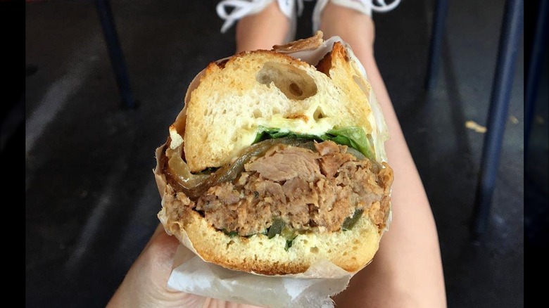 Person holding the roast pork sandwich fron Un Bien