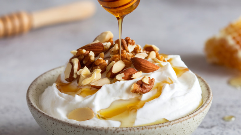 A bowl of yogurt with honey and nuts on top