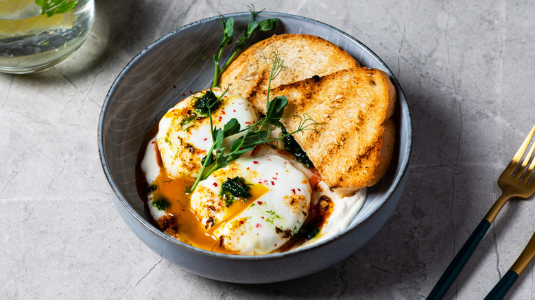 Poached eggs over greek yogurt and toast in a bowl