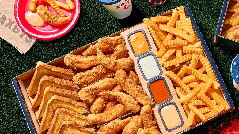 Open containers of sauces from Zaxbys with chicken toast and fries