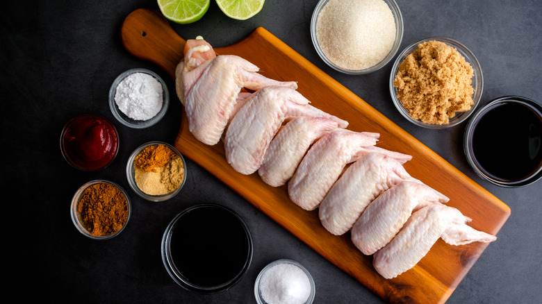 chicken wings on plank surrounded by seasonings and baking powder