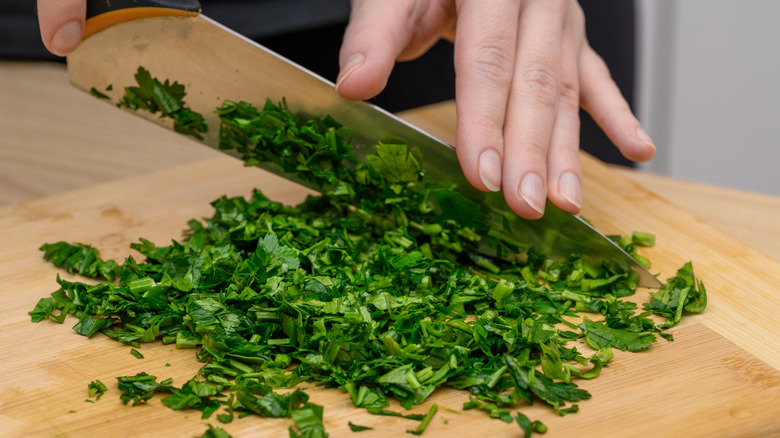 Person chopping up parsley on a cutting board