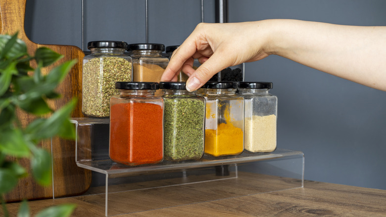 Hand selecting a jar from a spice rack