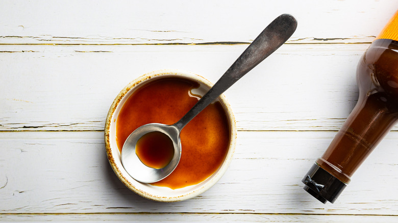 Worcestershire sauce bottle next to a bowl of sauce with a spoon