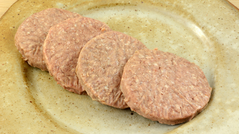 Frozen burger patties thawing on a plate