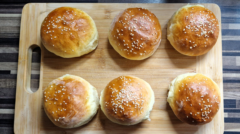Homemade burger buns on a wooden cutting board