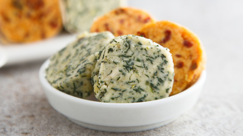 Spicy and herby rounds of compound butter in a small white bowl