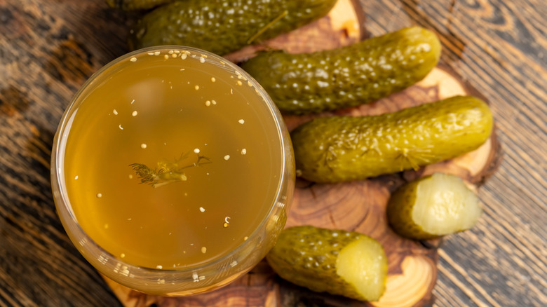 Pickles on a wood surface with pickle juice