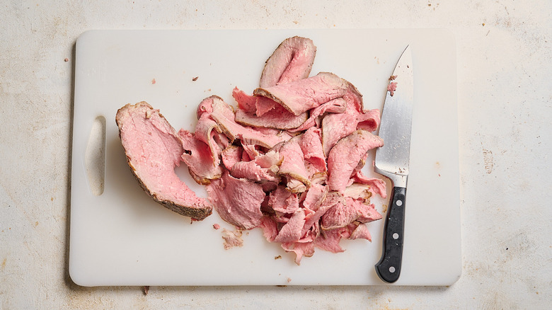 slicing roast beef on a cutting board