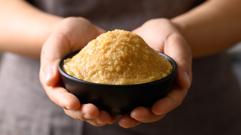 Hands holding a bowl of white miso paste