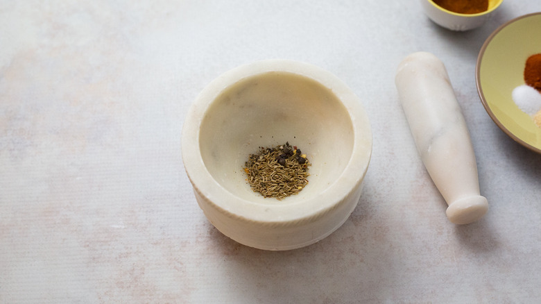 whole spices in gray mortar