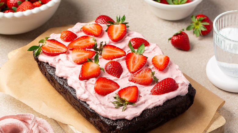 Image of single layer homemade chocolate cake topped with pink frosting and strawberry slices.