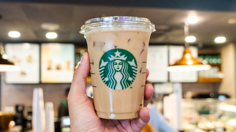 Person holding a Starbucks coffee up inside store