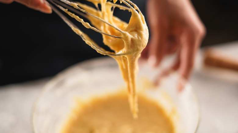 Closeup of person whisking yellow cake batter in a bowl.