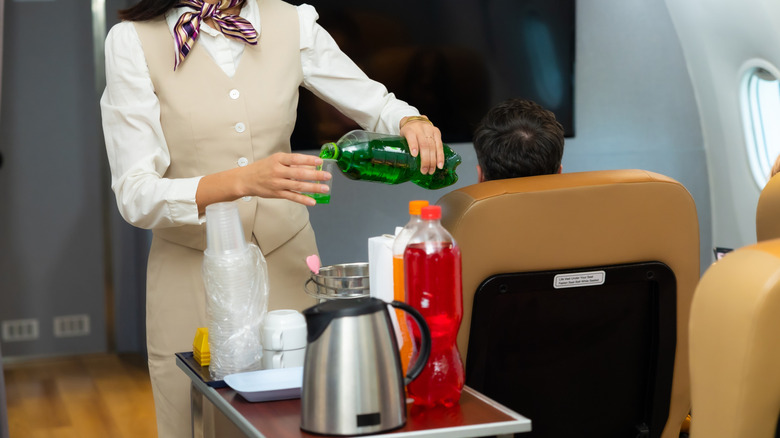 Flight attendant serving drinks to passengers