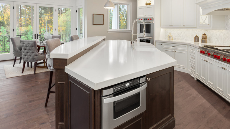 A spacious, modern kitchen with a two-tiered kitchen island with a marble countertop