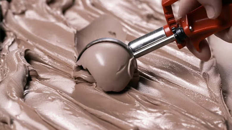 Employee scooping chocolate frozen custard.