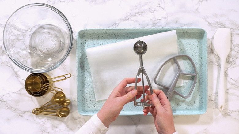 Baking tools and hand holding cookie dough scooper