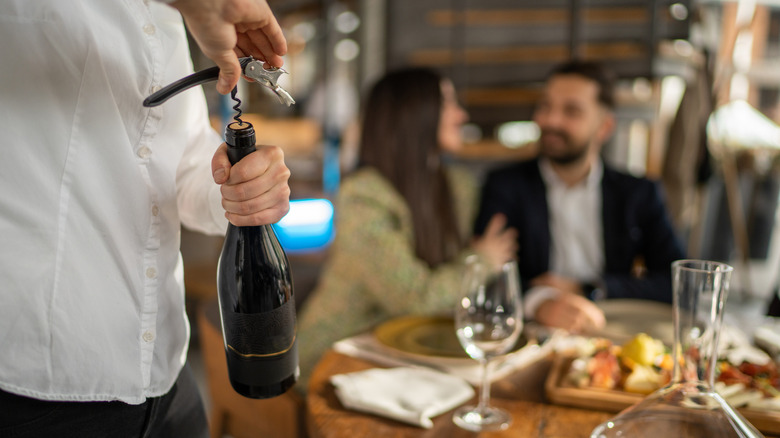 waiter opening wine at italian restaurant