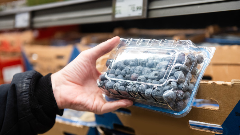 person looking at blueberries in grocery store