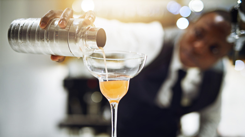 bartender pouring cocktail into glass