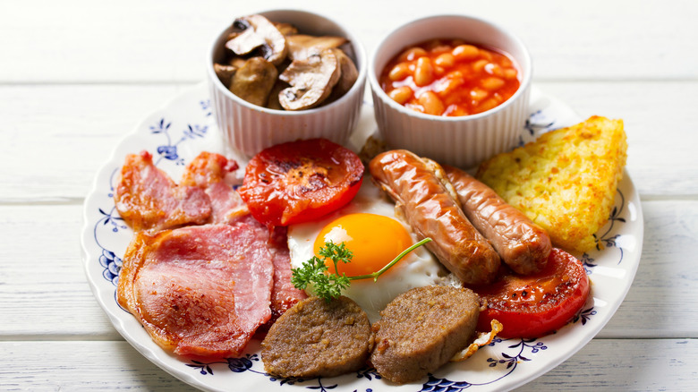 Classic English full breakfast with meat, beans, egg, tomato, mushrooms, and potatoes
