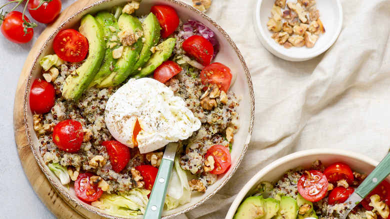 Breakfast quinoa bowls with avocado, poached egg, tomatoes, and nuts