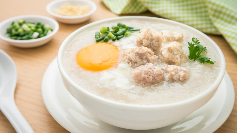 Bowl of congee with poached egg, herbs, and meat