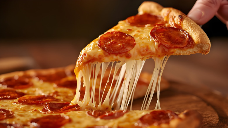 Pepperoni pizza being lifted from the pan