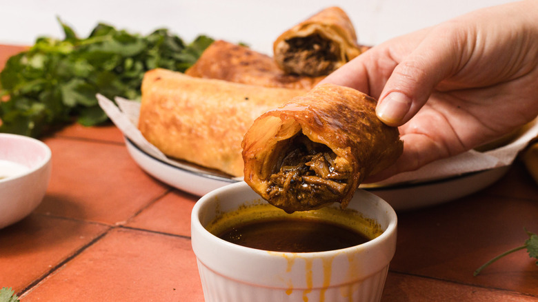 Dipping chimichanga half into consomme