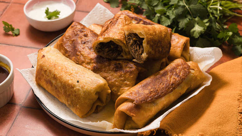 Fried chimichangas on plate with sour cream