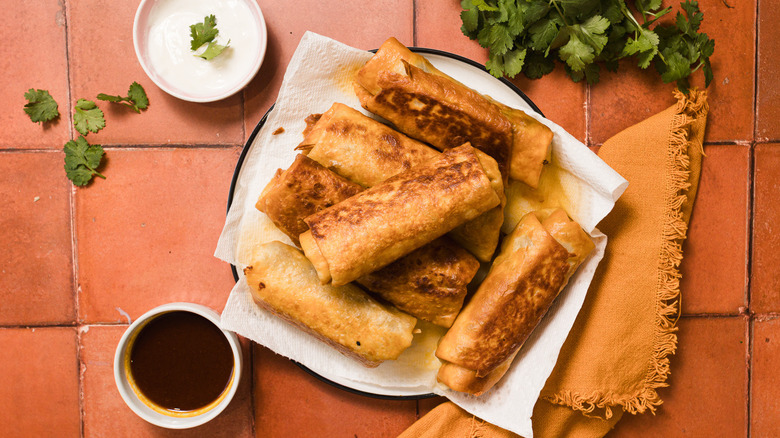 Fried chimichangas on plate with sour cream and consomme