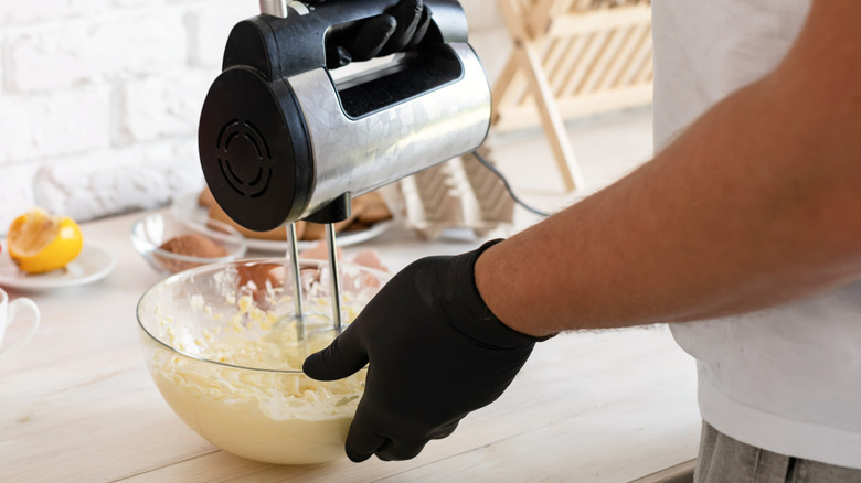 Person mixing a batter in a bowl with a hand mixer