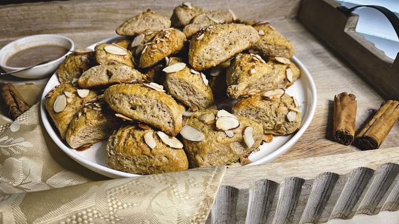 triangular scones with almonds on white plate with cinnamon stick