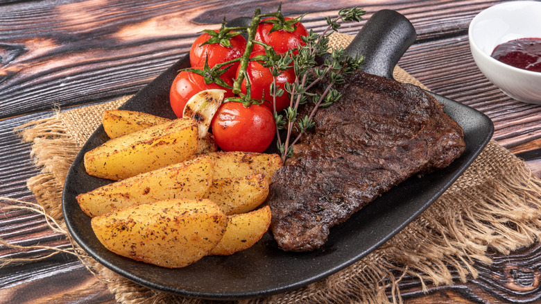 Steak, fries, and tomaotes served on a shovel