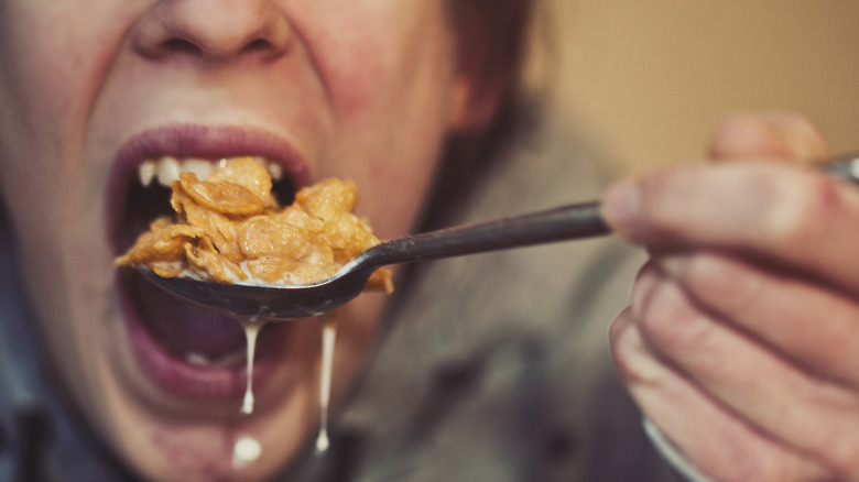 Person eating a giant spoonful of corn flakes