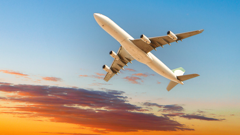 Bottom of an airplane against colorful sky