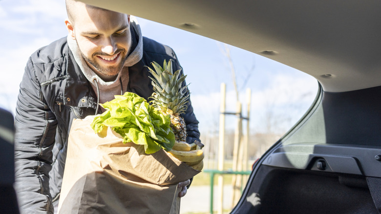 Man packing grocery bags into the trunk of car
