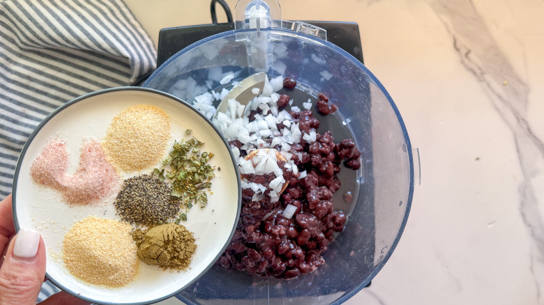 adding spices to food processor with black beans