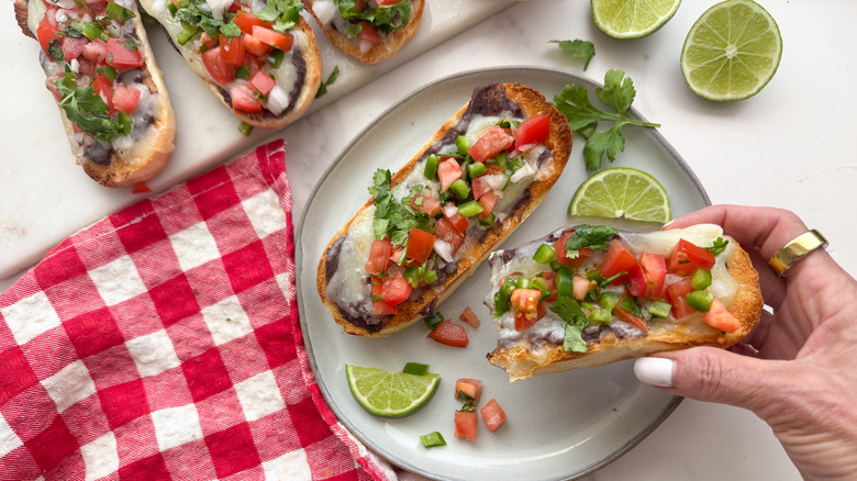 hand lifting pico de gallo topped mollete off plate