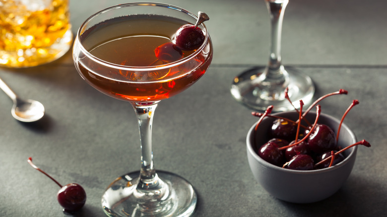 A Black Manhattan cocktail with a bowl of cherries