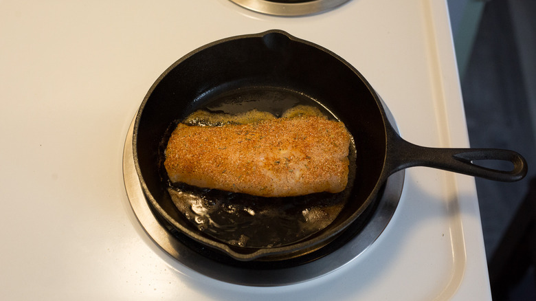 fish cooking in cast iron pan