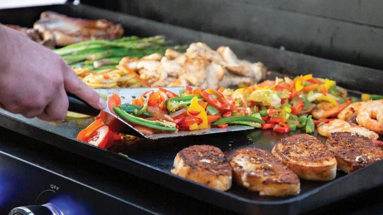 Person grilling on the Pit Boss grill's non-stick, ceramic cooking surface