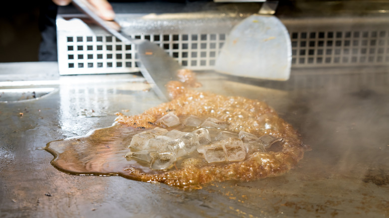 Ice cubes clean off a hot griddle surface.